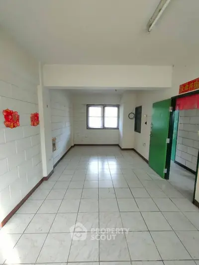 Spacious empty room with tiled floor and bright window, ideal for customization.