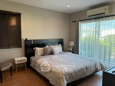 Spacious bedroom with modern decor and large window offering natural light.