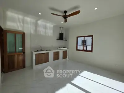 Modern kitchen with sleek design, featuring wooden cabinets, gas stove, and ceiling fan in a bright, airy space.