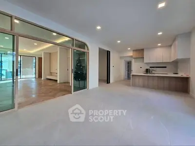 Spacious modern open-plan living area with sleek kitchen and glass partition, ideal for contemporary living.