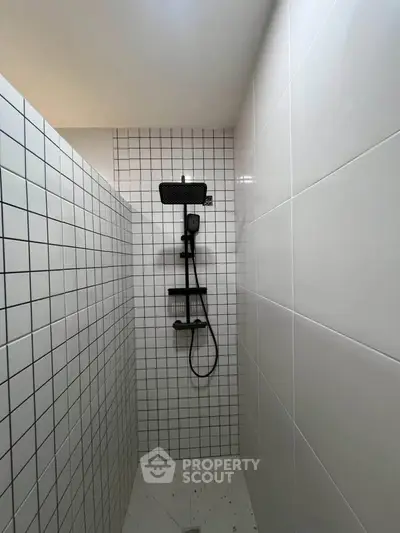 Modern minimalist bathroom with sleek shower fixtures and white tiled walls.