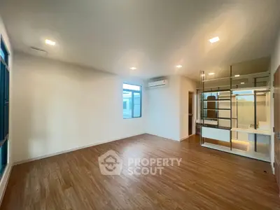Spacious empty room with wooden flooring and large windows, ideal for customization.