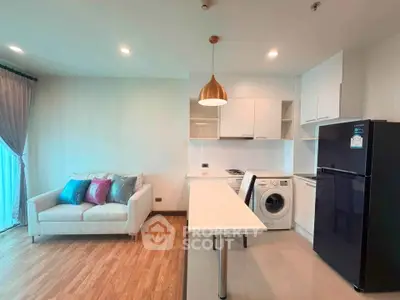Modern open-layout living room with kitchen, featuring a cozy sofa, washing machine, and sleek appliances.