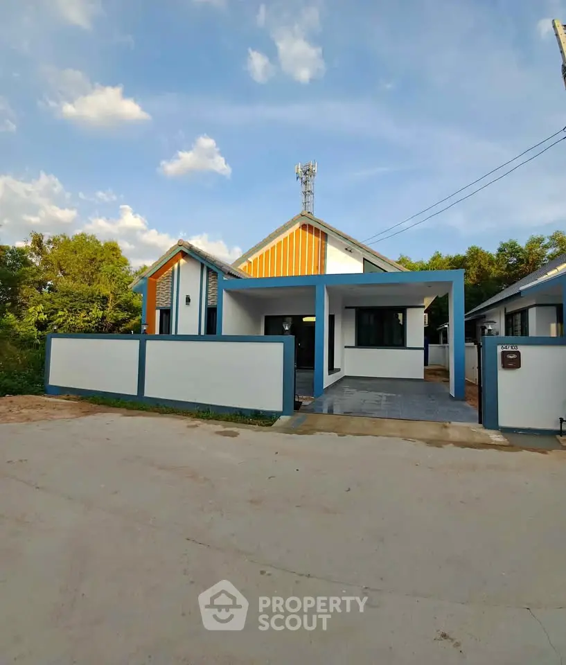 Charming modern house with blue accents and spacious driveway under clear skies.