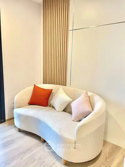 Stylish modern living room with elegant curved sofa and decorative pillows, perfect for cozy relaxation.