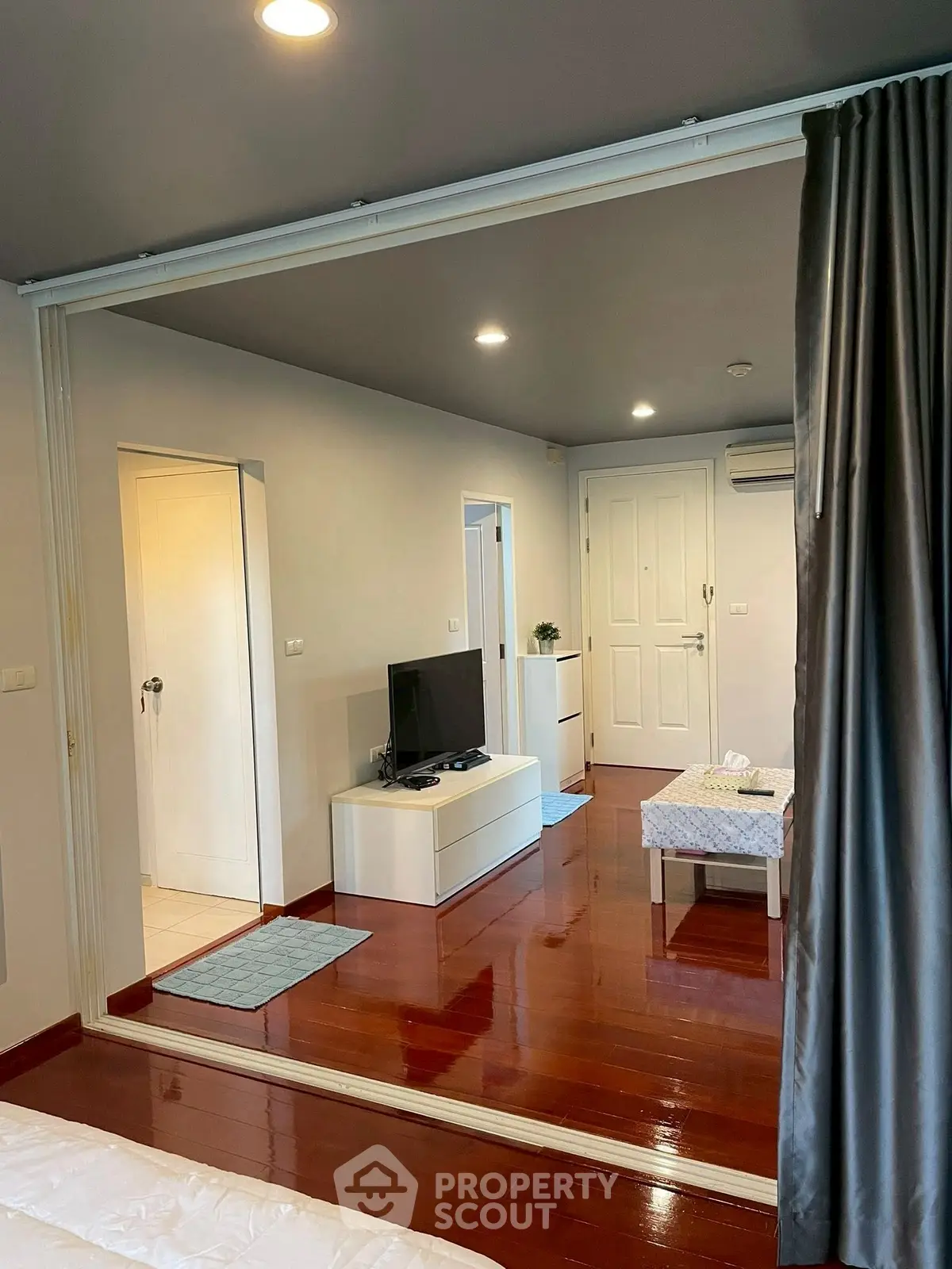 Modern living room with sleek design and wooden flooring, featuring a TV unit and cozy seating area.