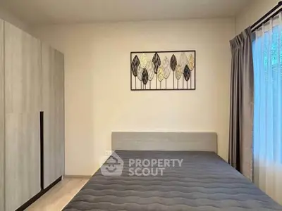 Modern bedroom with minimalist decor and large window for natural light.