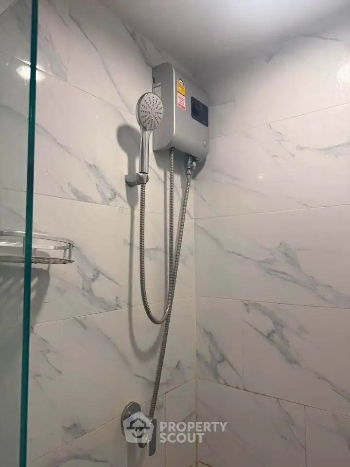Modern bathroom with sleek showerhead and marble tiles, perfect for a luxurious home experience.