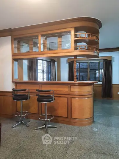 Elegant home bar with wooden cabinetry and stylish bar stools in a cozy living space.