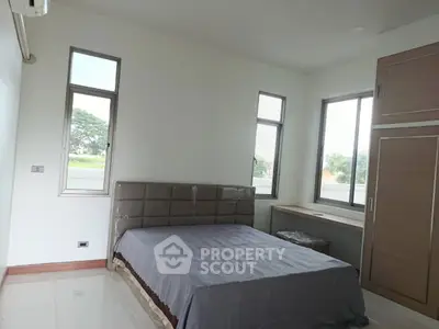 Spacious bedroom with large windows and modern furnishings, offering a serene view.