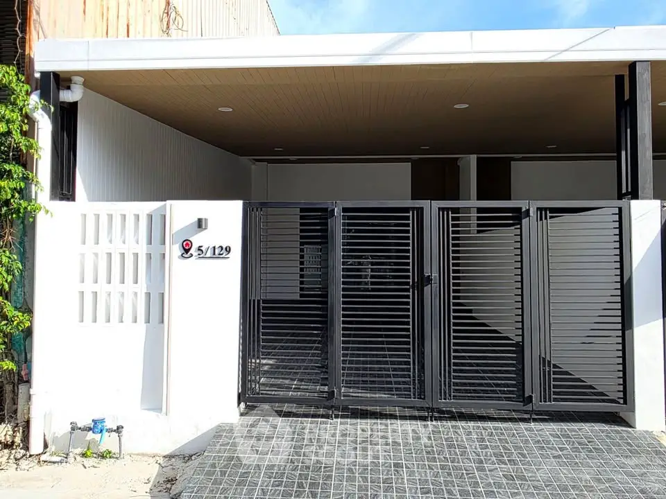 Modern gated entrance with sleek black metal design and white walls
