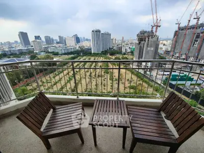 Stunning city view from a high-rise balcony with modern wooden furniture.