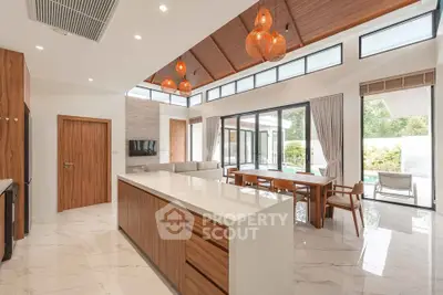 Luxurious open-plan living room with modern kitchen and pool view, featuring elegant lighting and high ceilings.