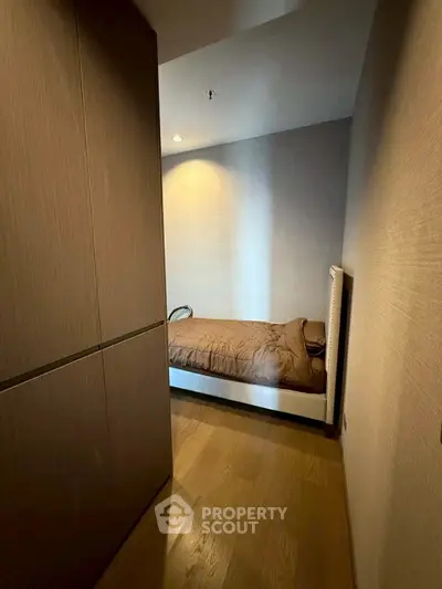 Cozy small bedroom with wooden flooring and soft lighting