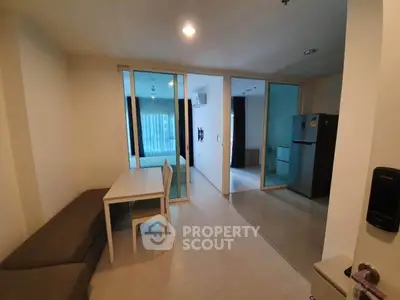 Modern apartment interior with open layout, featuring dining area, bedroom, and kitchen with sleek appliances.