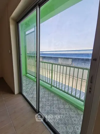 Spacious balcony with sliding glass doors and modern railing, offering a serene outdoor view.