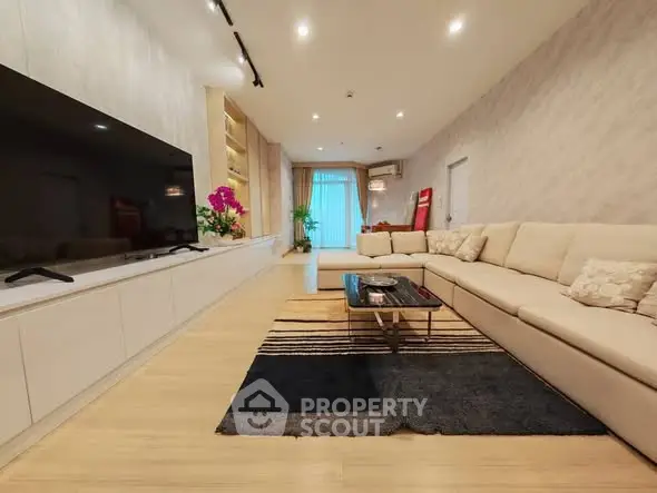 Spacious modern living room with elegant decor and large TV, perfect for relaxation and entertainment.