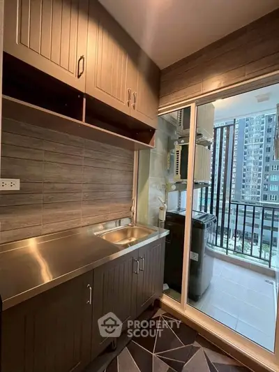 Modern kitchen with stainless steel countertop and balcony view in urban apartment