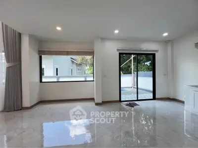 Spacious modern living room with large windows and sliding glass door to patio.