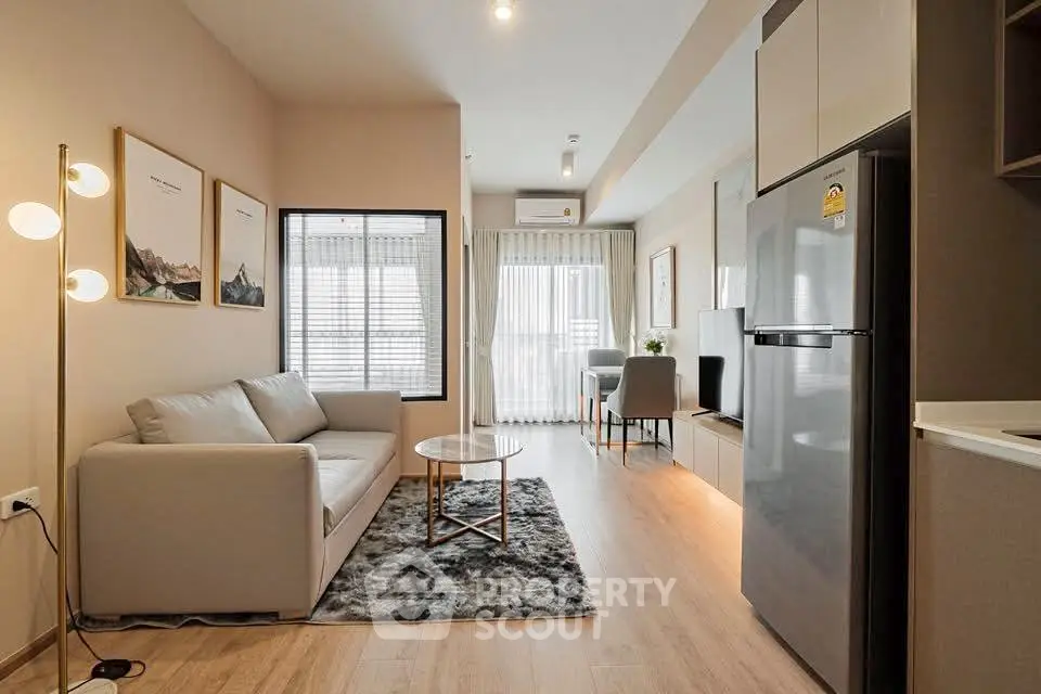 Modern living room with stylish decor and open layout, featuring a cozy sofa and sleek kitchen area.