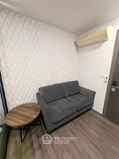 Cozy living room with modern gray sofa and stylish wooden side table, featuring elegant wallpaper and air conditioning.