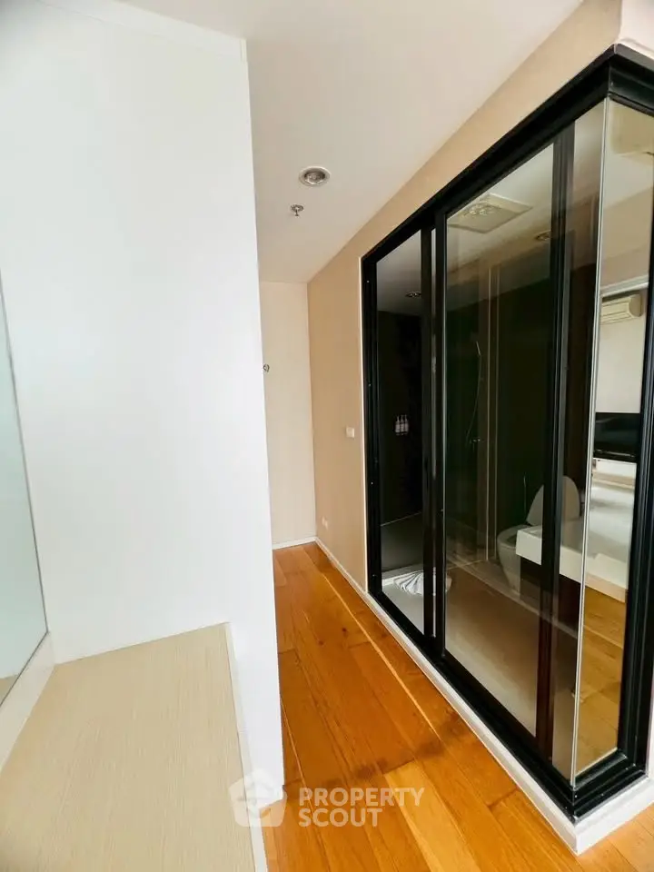 Modern apartment hallway with wooden flooring and glass shower enclosure