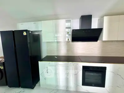 Modern kitchen with sleek black appliances and white cabinetry, featuring a built-in oven and stylish range hood.