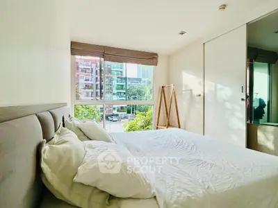 Bright and airy bedroom with large window and modern decor in urban apartment.