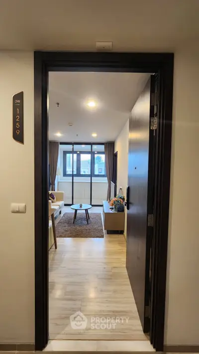 Modern apartment entrance leading to a cozy living room with large windows and stylish decor.