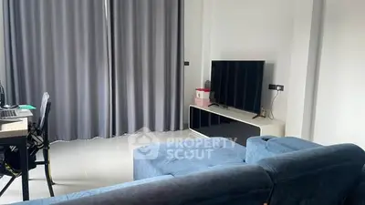 Modern living room with blue sofa and large TV, ideal for relaxation and entertainment.