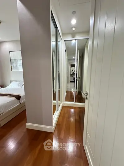 Spacious bedroom with mirrored closet doors and elegant wooden flooring