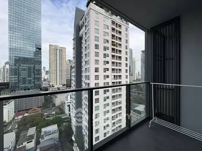 Modern city view from a high-rise balcony with sleek glass railing and urban skyline.
