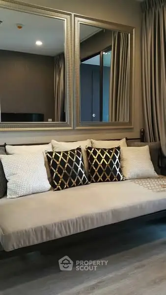Elegant living room with stylish sofa and decorative pillows, featuring large mirrors and modern decor.