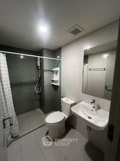 Modern bathroom with sleek fixtures and spacious shower area in contemporary apartment.
