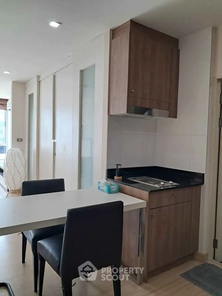 Modern kitchen with sleek cabinetry and dining area in a stylish apartment.
