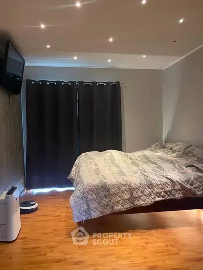 Cozy bedroom with modern lighting and wooden flooring, featuring a comfortable bed and stylish decor.
