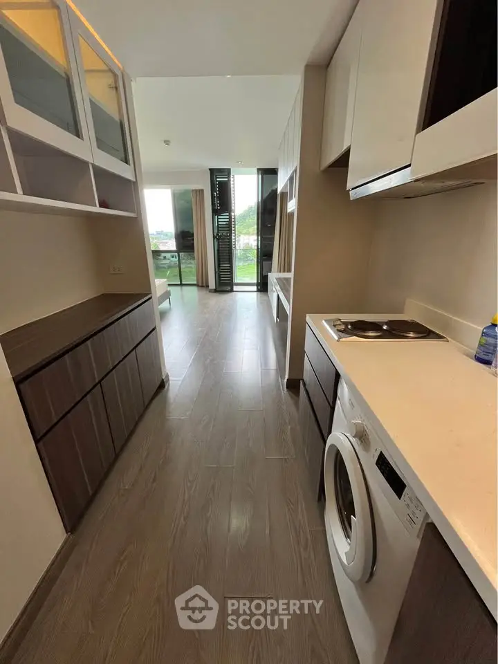 Modern kitchen with washing machine and sleek cabinetry in open layout apartment