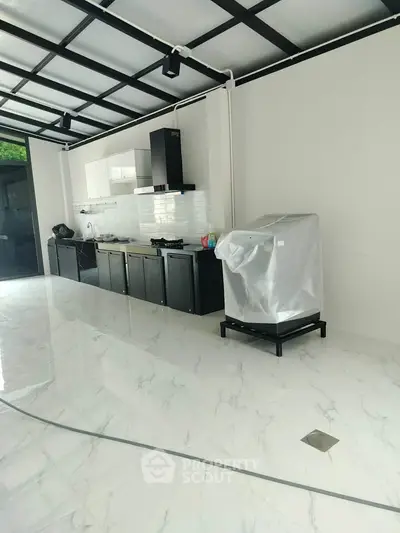 Modern kitchen with sleek black and white design, featuring marble flooring and ample natural light.