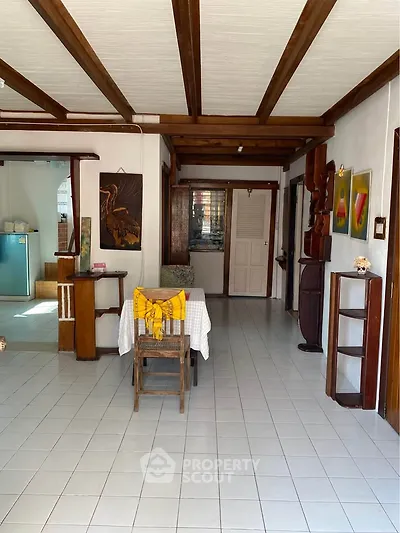 Charming open-layout living space with rustic wooden beams and artistic decor, perfect for cozy gatherings.