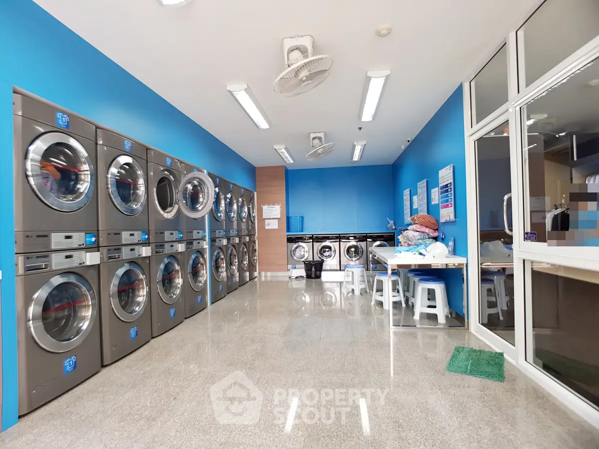 Modern laundry room with multiple washing machines and bright blue walls in a residential building.