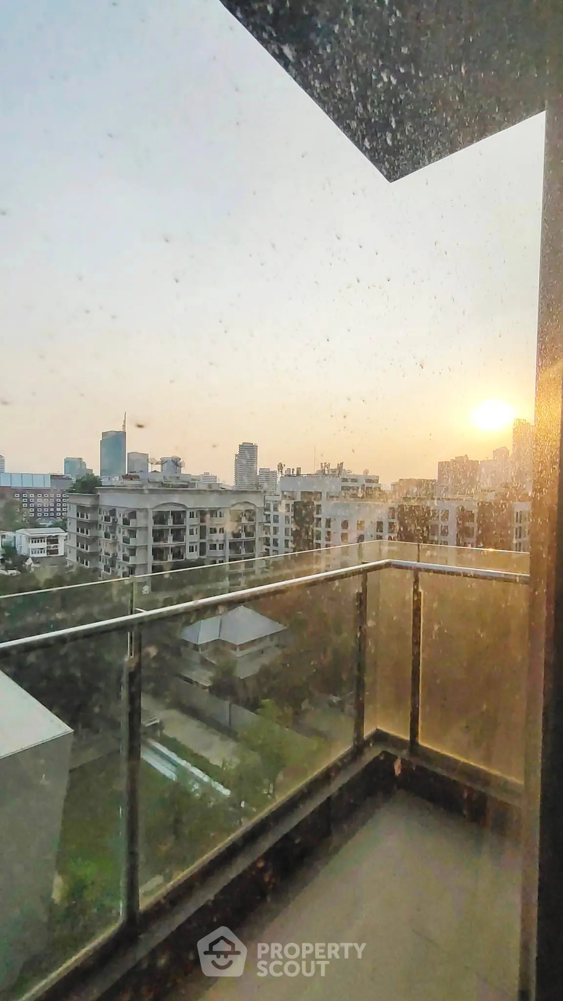 Stunning city view from a high-rise balcony at sunset, showcasing urban skyline and serene atmosphere.