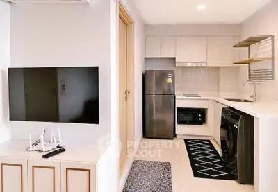 Modern kitchen with sleek appliances and stylish living area in a compact open layout apartment.