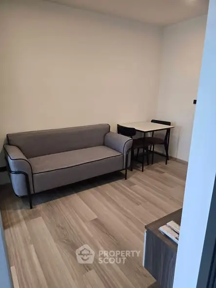 Modern living room with sleek gray sofa and compact dining area, perfect for urban living.