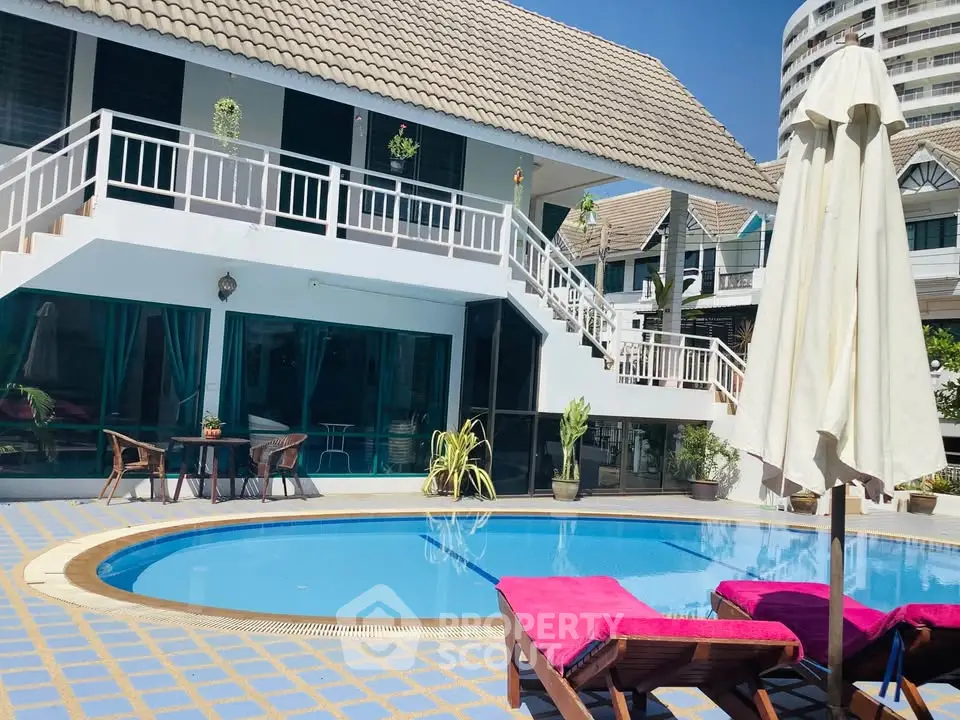 Charming villa with poolside relaxation area and sun loungers, perfect for tropical living.