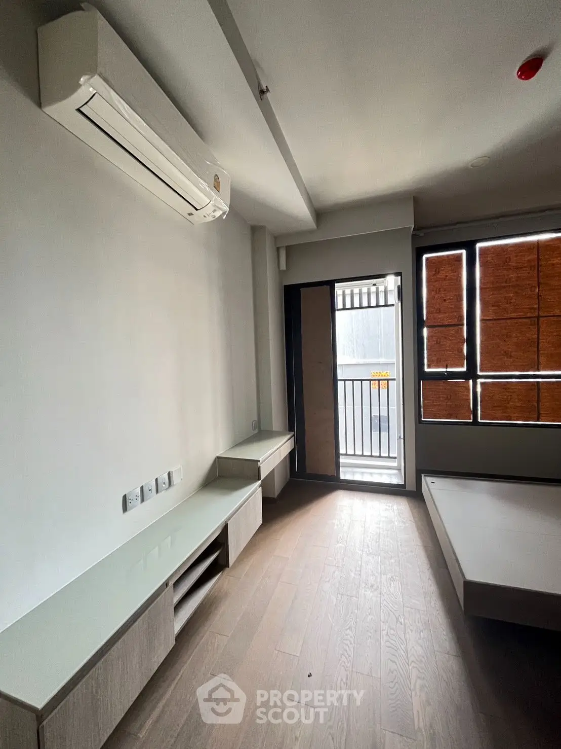 Modern minimalist bedroom with air conditioning and balcony access