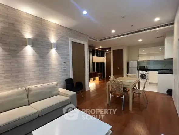 Modern open-plan living room with kitchen, featuring cozy sofa and dining area.