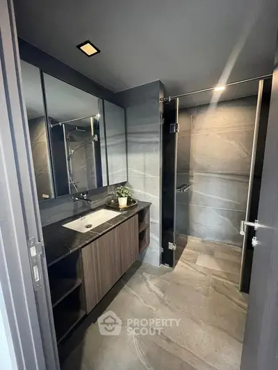 Modern bathroom with sleek design, featuring a glass shower and stylish vanity in a contemporary home.