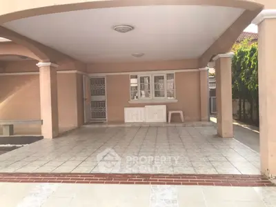 Spacious covered parking area in a residential property with tiled flooring and secure gated entrance.