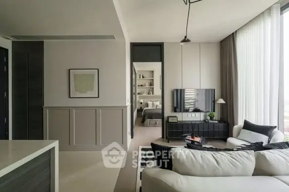 Modern living room with stylish decor and open view to bedroom, featuring cozy seating and natural light.