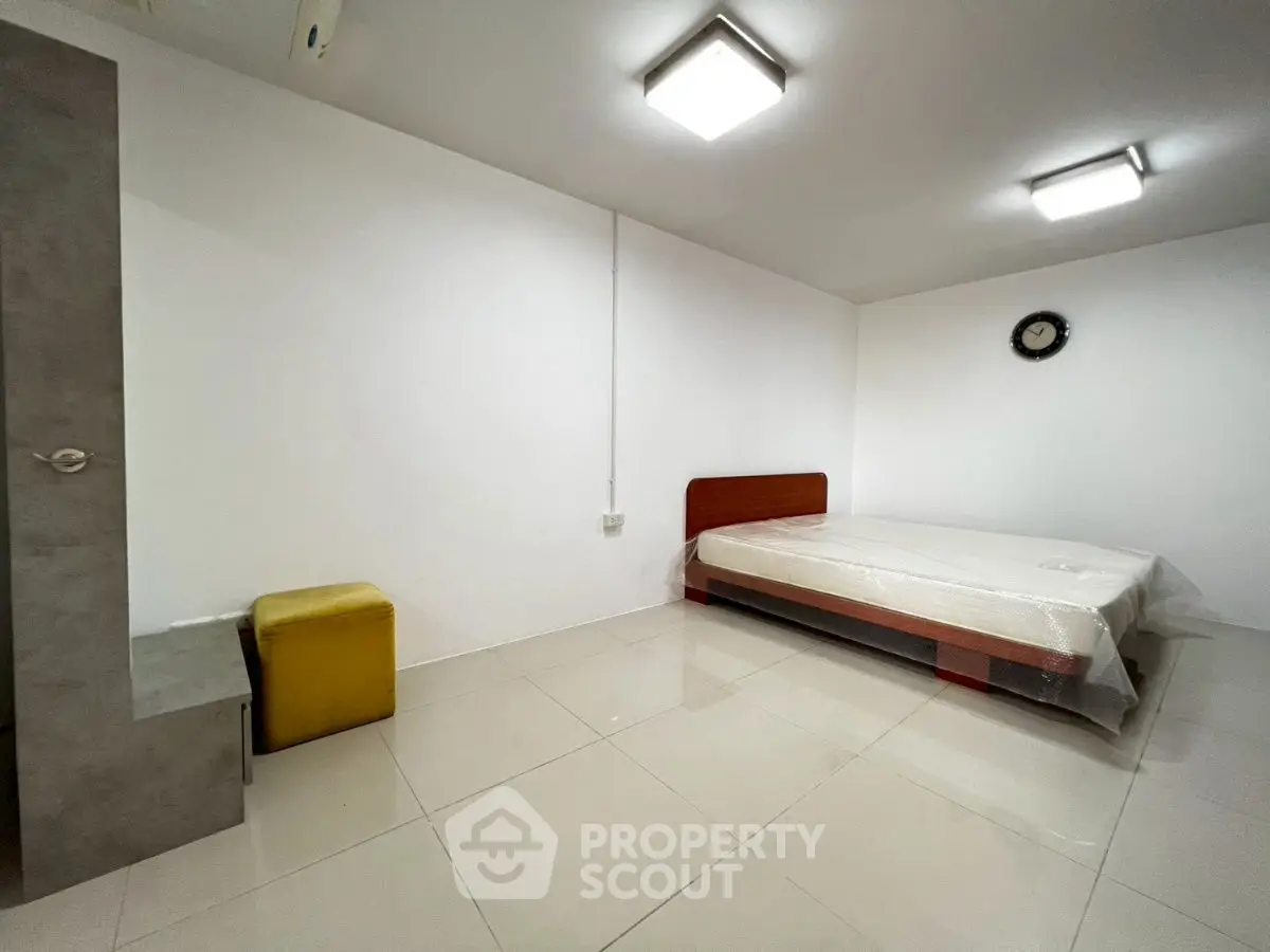 Minimalist bedroom with modern lighting and tiled flooring, featuring a bed and a small seating area.